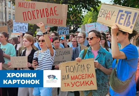 Фотографія протесту з картонними плакатами, серед яких «Маселко покриває Князєва»; підпис «Хроніки картонок».